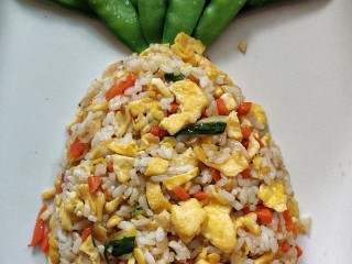 菠萝蛋包饭,把炒好的米饭放入盘里，用勺子整理成菠萝形状，上窄下宽。