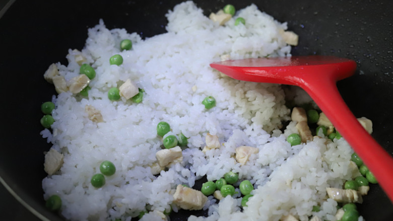 菠萝鸡丁炒饭,加入煮好的米饭，不断翻炒，让米饭受热均匀，米饭炒香的同时鸡丁和豌豆也能熟透。
