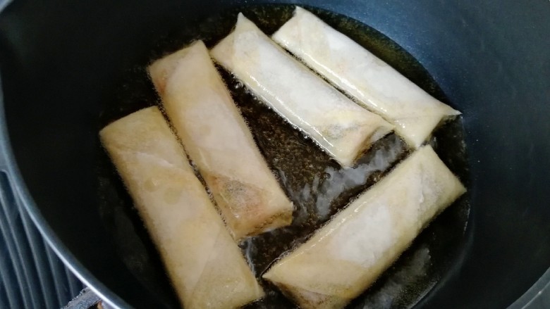 炸春卷,炸锅内倒入多一点菜籽油烧热，放入做好的春卷。