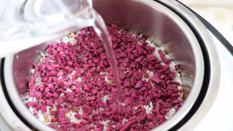 紫薯麦粒米饭,顶层放上紫薯丁，同样平铺开。倒入水，因为是隔着小滤网的，所有水分需要加到稍微超过米饭即可，一般的话，不能超过食物面的1cm。