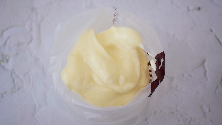 酸奶舒芙蕾蛋糕,将拌匀的蛋糕糊装入裱花袋中备用，没有的话可以直接用勺子