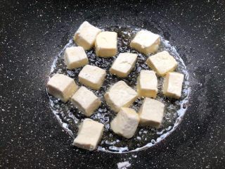 杂蔬豆腐,锅里放入适量油烧热，把裹好淀粉的豆腐放到锅里煎至六面金黄，煎好夹入盘里待用。