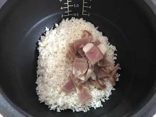  豌豆咸肉焖饭,把淘洗干净的糯米和咸肉一起放入电饭煲。