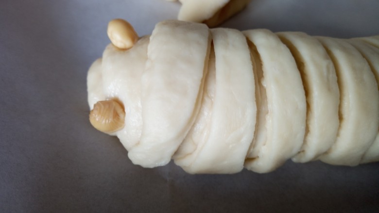 果酱夹心的毛毛虫面包,涂果酱的半边卷起。把宽条绕在上面装饰上豆粒