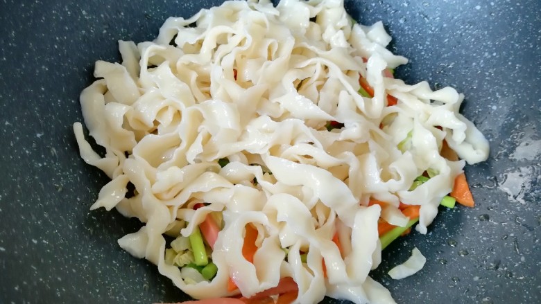 蔬菜火腿炒刀削面,下入煮好的刀削面翻炒均匀。