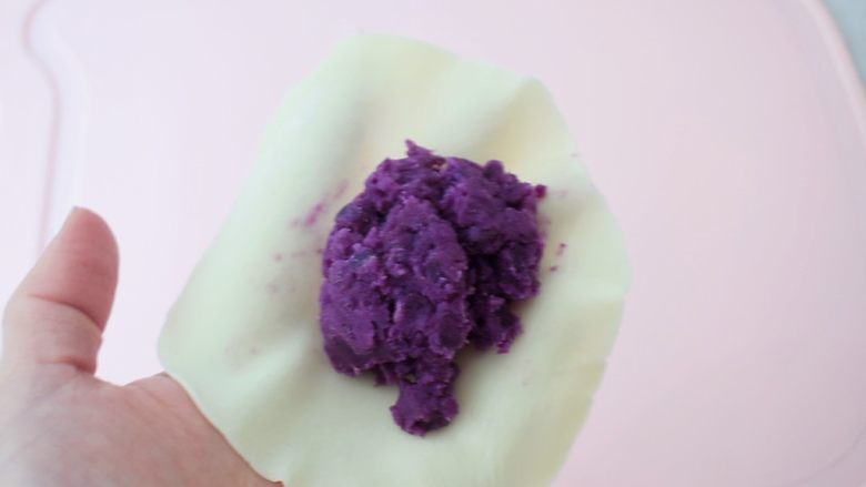 饺子皮紫薯饼,用左手托住饼皮，中间放入适量的紫薯泥