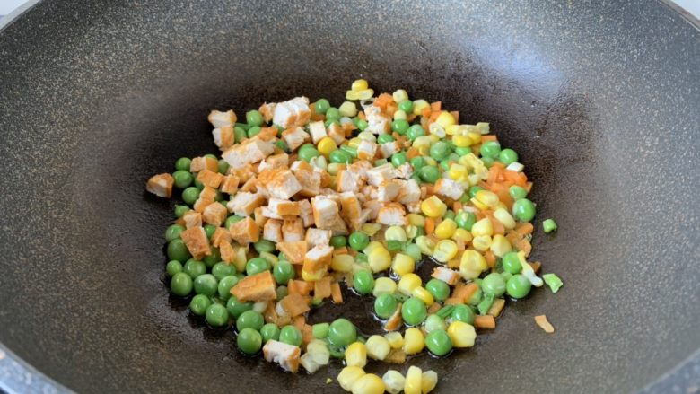 春日包菜饭便当,放入胡萝卜、豌豆、玉米、鸡肉丁，翻炒1分钟。