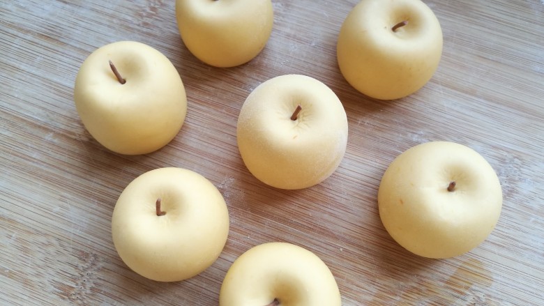 金苹果馒头（肉松包）,在凹下的中间挨个按上苹果把，金黄色的小苹果做好了。
山东有一种吃起来口感面面的，名字叫金帅苹果，就是这个样子。