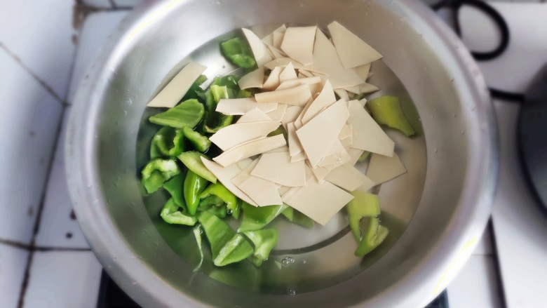家常尖椒炒豆片,水开后将食材放入，焯水。