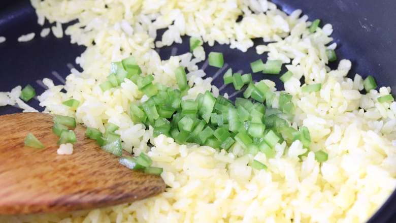 金镶银(黄金炒饭),待米粒都松散开，而且蛋液也包裹了米粒后，加入盐、白胡椒粉，以及青椒粒，翻炒。