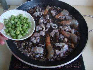 西班牙墨汁海鲜饭,放入海鲜和豌豆煮熟，收干汤汁
