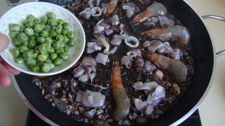 西班牙墨汁海鲜饭,放入海鲜和豌豆煮熟，收干汤汁