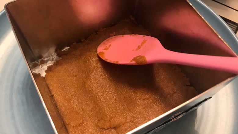 酸奶芒果蛋糕,饼干泥放入包好锡纸的底部，压实压平，冷藏15分钟以上。