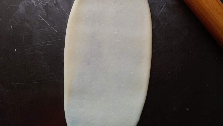 毛毛虫豆沙面包,擀成略长的椭圆形（擀的时候动作轻一点，防止豆沙挤出来）