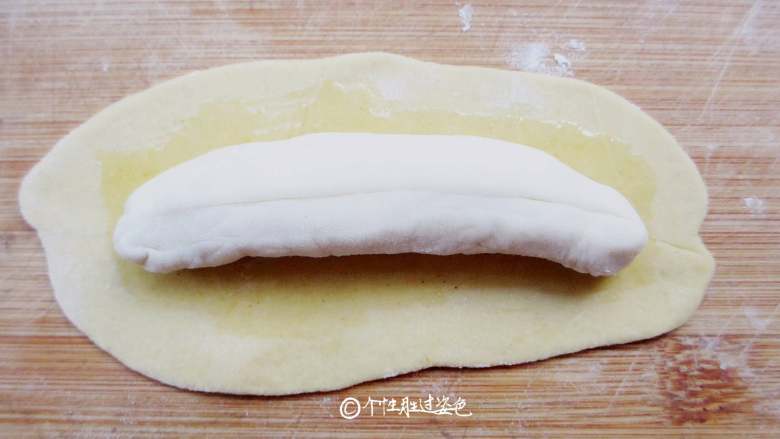 仿真香蕉馒头,把白面条放在黄面皮中间。 刷油是为了隔开里外两层面皮，便于蒸好后可以轻松的剥开‘香蕉皮’