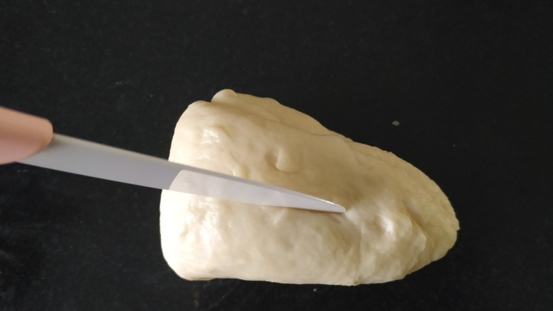 椰蓉心形面包,用锋利的小刀在最厚的那边中间切一刀，尾部留出两三厘米不切；