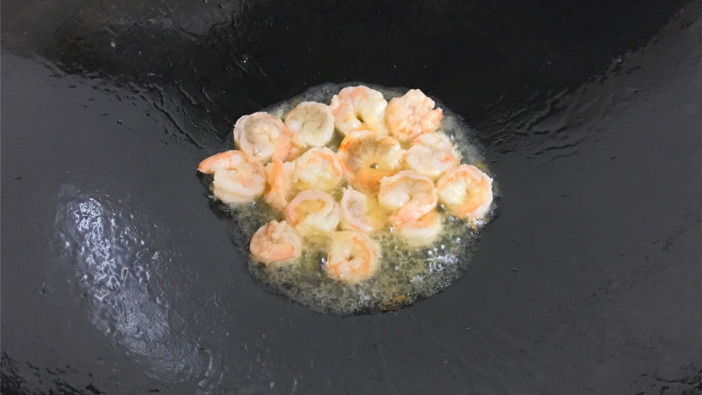 芦笋虾球,锅中到入适量油，烧热后放入腌制好的大虾用锅铲划散。