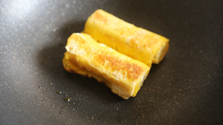 无敌简单的香蕉土司卷,将卷好的香蕉卷放入锅中，小火煎至两面金黄。