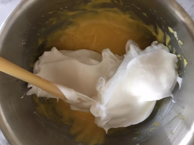 蛋糕界的网红--古早蛋糕,用刮刀铲出三分之一蛋白加入蛋黄糊中，像炒菜一样翻拌均匀，然后把蛋黄糊倒入剩余的蛋白中，继续翻拌均匀，大幅度快速温柔的翻拌，以防消泡哦。