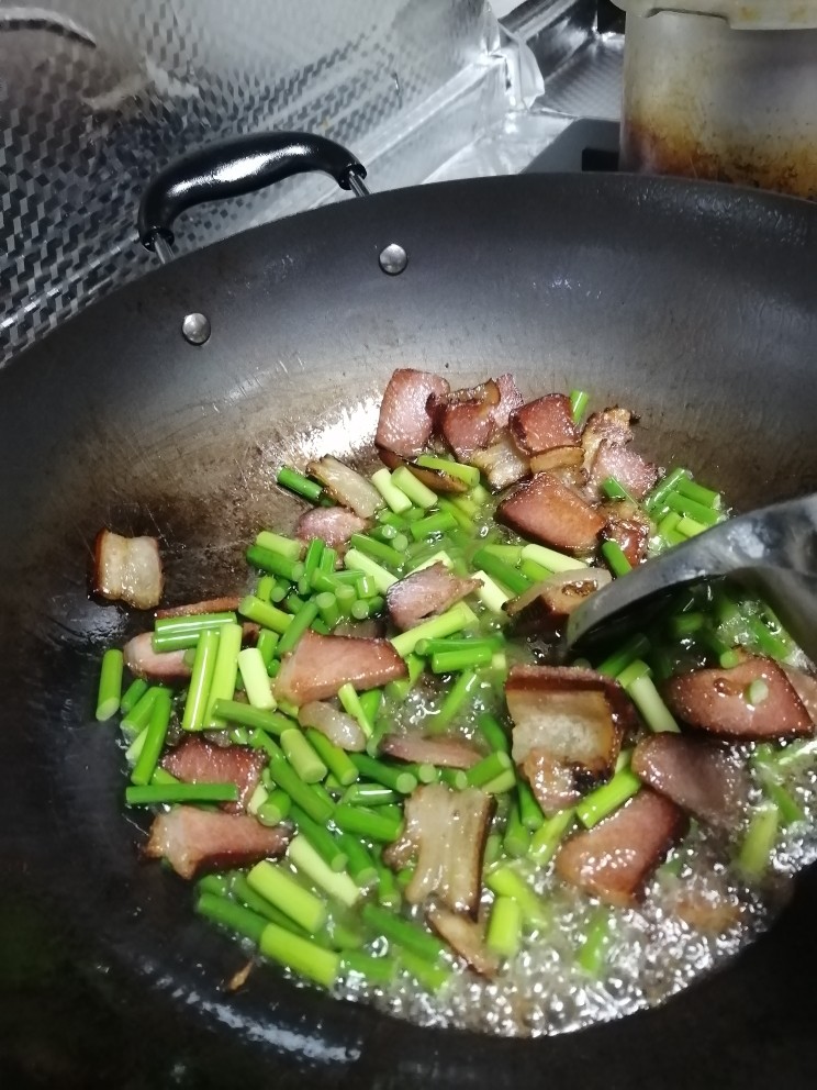 腊肉炒蒜苔,然后加入少许盐，辣椒粉和酿造酱油一起炒半分钟，加入点点水一起炒。