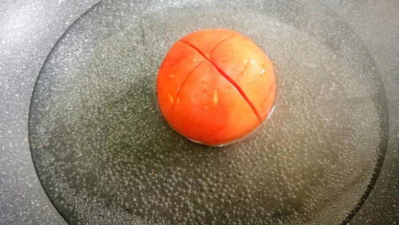 爆红网络的一个番茄饭,番茄顶部用刀划十字架。放入锅中煮两分钟待皮分离，取出撕掉皮。