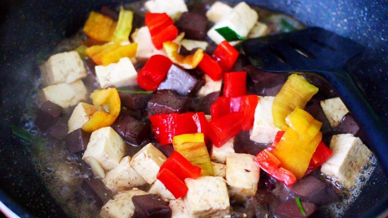 双椒烩双色豆腐,这个时候加入切块的红椒和黄椒，大火翻炒片刻。