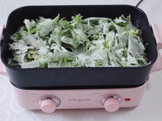 芹菜叶麦饭,锅中倒入适量的清水烧开后，把搅拌均匀的芹菜叶放入锅中。