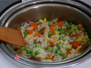 蔬菜腊肠饭,将锅中的米饭连同米汤倒入脱糖饭煲中，用木铲拌均匀