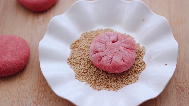 粉嫩蔓越莓果仁芝麻饼,把没有花纹的一面，蘸上一层薄薄的白芝麻。