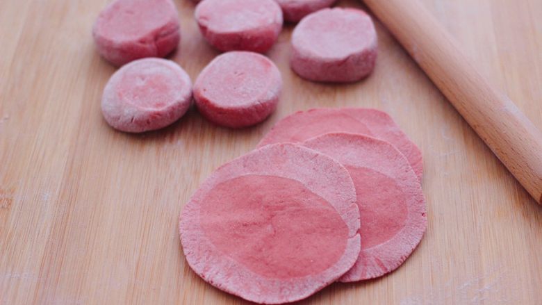 粉嫩蔓越莓果仁芝麻饼,把剂子摁扁后，用擀面杖擀成圆形薄面皮。
