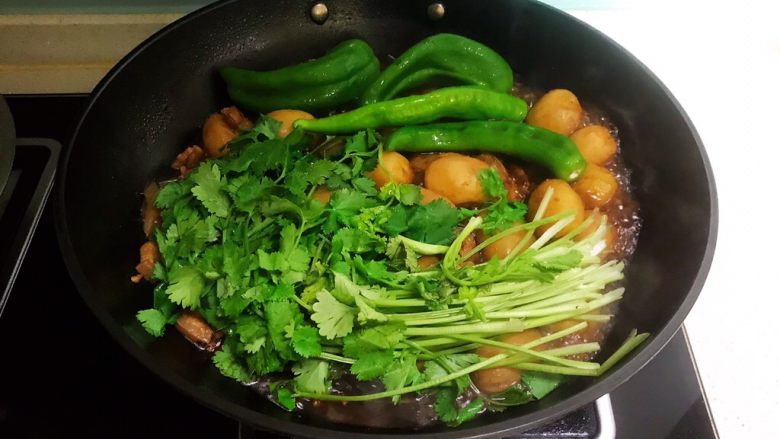 五花肉焖小土豆,加入小辣椒和香菜，盖上锅盖，继续烧10分钟