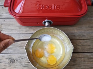 多啦a梦的铃铛烧,将3个鸡蛋磕进容器，加入50克白糖，要想甜加点盐，再加入1克的盐。