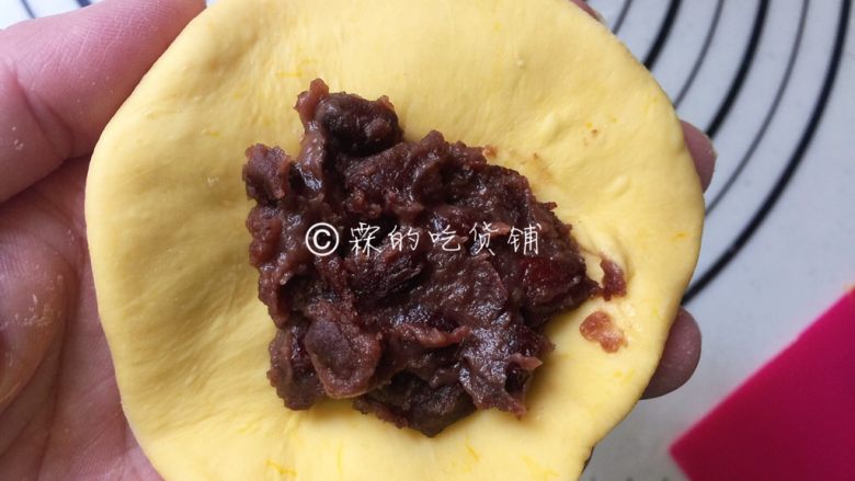 奶香南瓜蜜红豆馅发面饼,剂子揉圆、按扁，尽量按成中间厚四周稍薄的，随后中间放上蜜红豆馅。