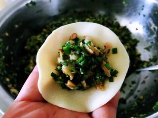 种菇韭菜饺子,左手拿起一个饺子皮，放入饺子馅，用左手和右手的虎口处一捏就成了。