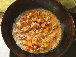 泰式香辣风味烧鸡翅,中小火煎至鸡皮收缩，下胡萝卜块，稍稍翻炒约1分钟左右。加入热水，水量需没过食材。