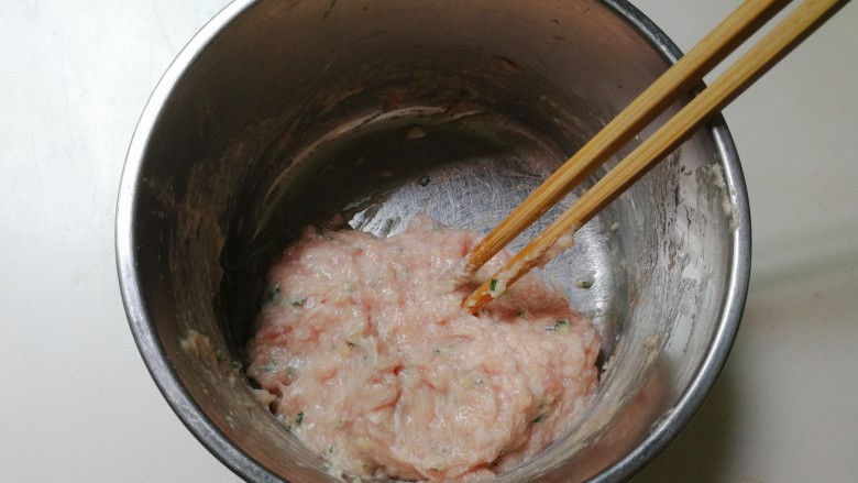 蚕豆仁汆汤丸子,再次顺时针搅拌至有粘性的肉糊，用筷子挑去肉糊摔打几下，摔出里面空气
