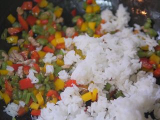 蔬菜虾仁焗饭,把米饭加入翻炒好的蔬菜中翻拌均匀