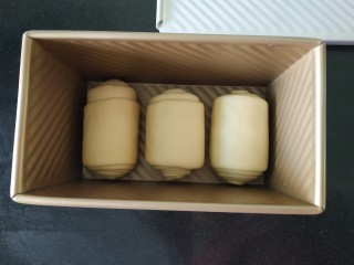 一次性发酵更省时间的奶香吐司~,把所有剂子都卷好，每个吐司盒子里均匀的摆放三个卷；