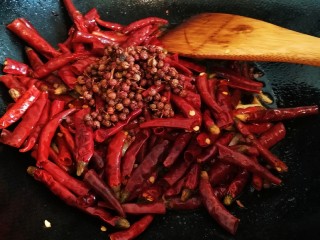 椒香辣子鸡,倒入干辣椒段和花椒，翻炒一分钟，使其充分出味。