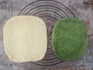 抹茶蜜豆土司,把两个面团擀成宽一点的长方形，原味面团比抹茶味的要稍微大一圈