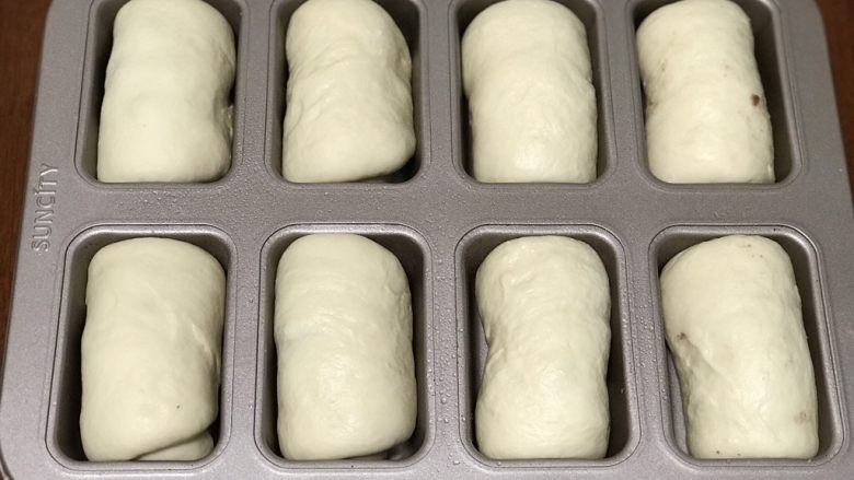 奶香蜜豆面包卷,卷成卷放入模具中，在温度是33-38度的环境下发酵至1.5倍大（大约40-60分钟）。