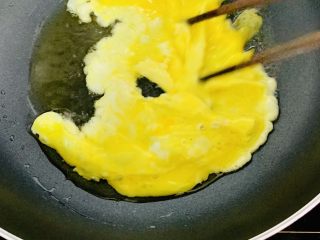 风味牛肉肠焗饭,先把一个鸡蛋轻轻打散，放入热油中。用筷子快速划拌。