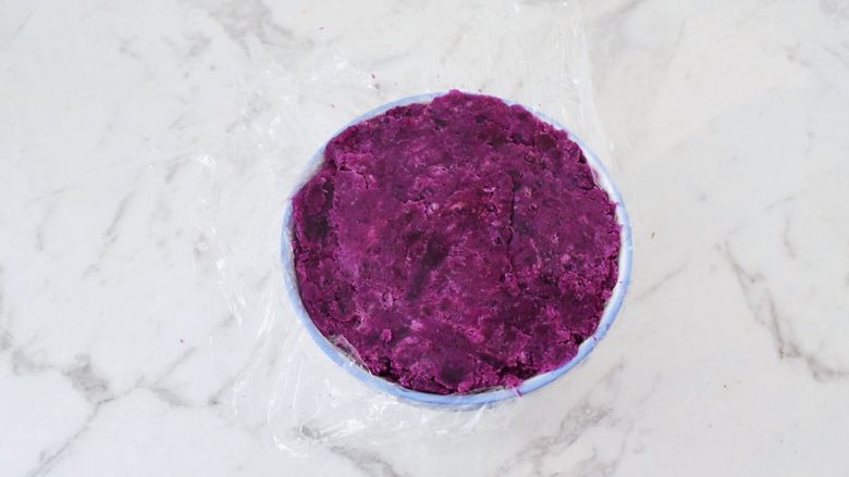 酸奶紫薯泥,碗铺上保鲜膜，这样方便后面脱模，再把紫薯泥放入碗中，用勺子压实