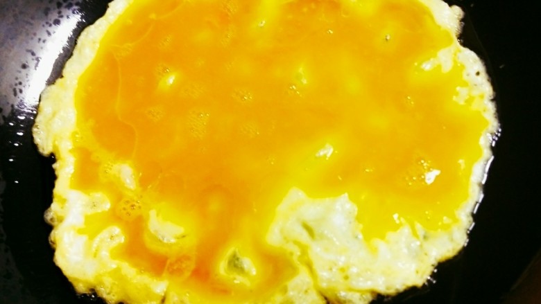 韭菜花炒鸡蛋,锅中倒油，油热后加入打碎的鸡蛋，小火慢煎