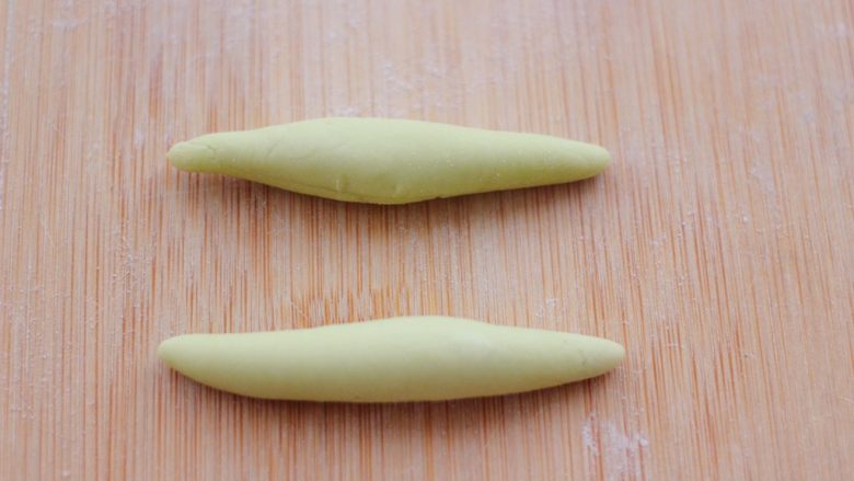 花样粽子馒头,把菠菜面团，分成每个6克左右的剂子，用手搓成椭圆形。