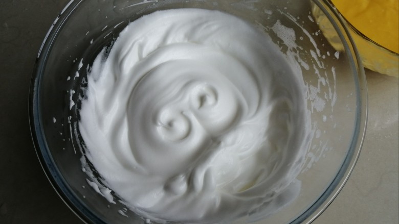 戚风纸杯蛋糕,用电动打蛋器把蛋清打至粗泡后，倒入1/2糖，打至有纹路的状态，再倒入剩余的糖，一直打发至干性发泡。