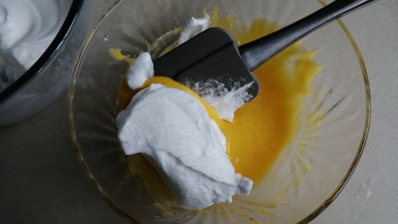 戚风纸杯蛋糕,用刮刀取1/3打发好的蛋白霜到蛋黄糊里，从底部向上翻拌并切拌均匀
