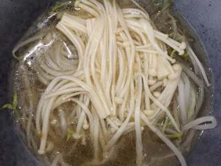 酸汤肥牛,把豆芽和金针菇放在一大碗中，把煮好的酸汤倒入。