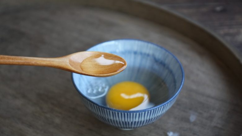 鹅蛋鸡肉炒蒜苔,一枚鹅蛋磕入碗中，放入1小勺的白糯米酒。