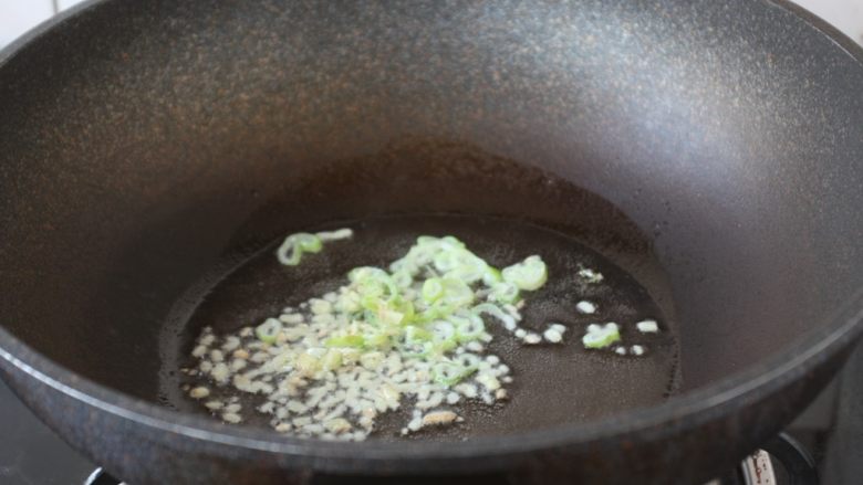 鹅蛋鸡肉炒蒜苔,热锅凉油，放入葱花、姜末，炒出香味。